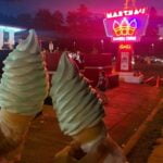 large-ice-cream-cones-held-in-the-evening-with-marthas-lighted-sign-in-the-background